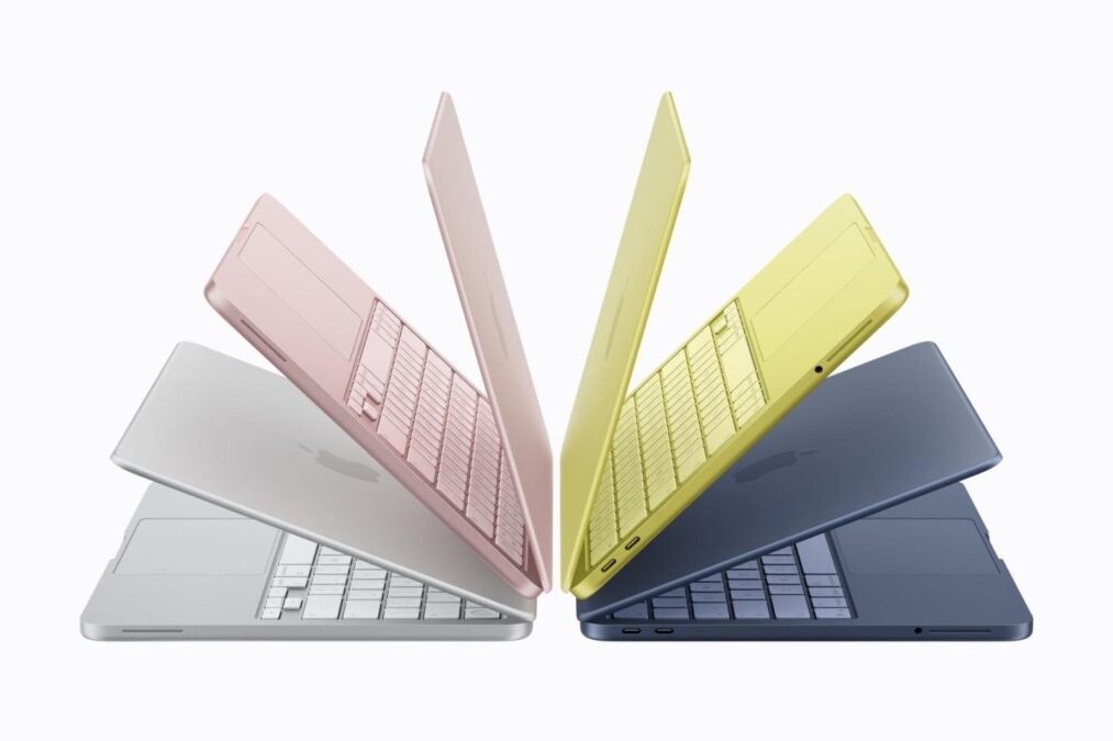 Apple MacBook lineup in silver, pink, yellow, and dark blue arranged in fan formation.